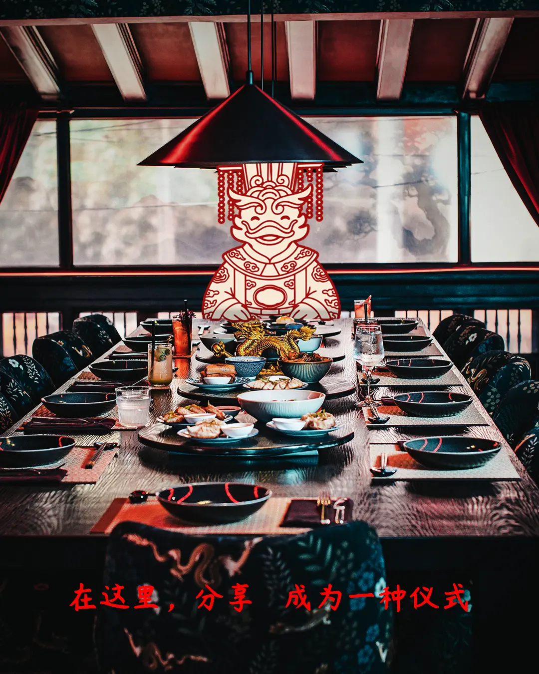 Long dining table set for a feast in a Chinese-style room, with a large red decorative figure hanging above the head of the table.