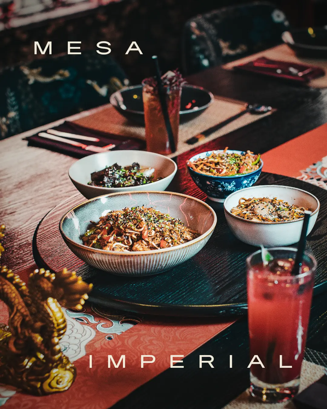 Table setting at a restaurant with multiple bowls of noodles and a pink cocktail; 'MESA IMPERIAL' text overlaid on the image.