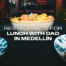 Banner image of a bowl of fried chicken and potatoes on a table with city lights in the background; text reads 'Restaurants for lunch with dad in Medellín'.